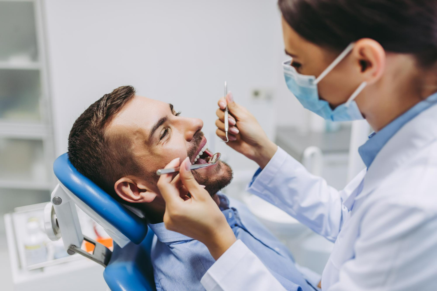 portrait-dentist-medical-mask-checking-patient-teeth-with-mirror-dental-clinic